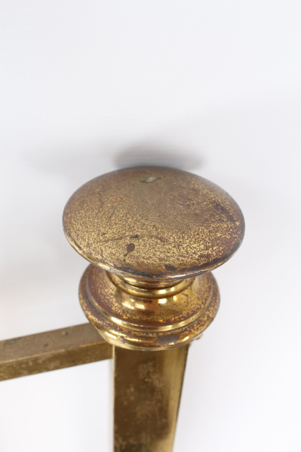 A Victorian brass single bed frame featuring a gently curved top rail, vertical spindles, turned finials, and original wheel castors. View IX