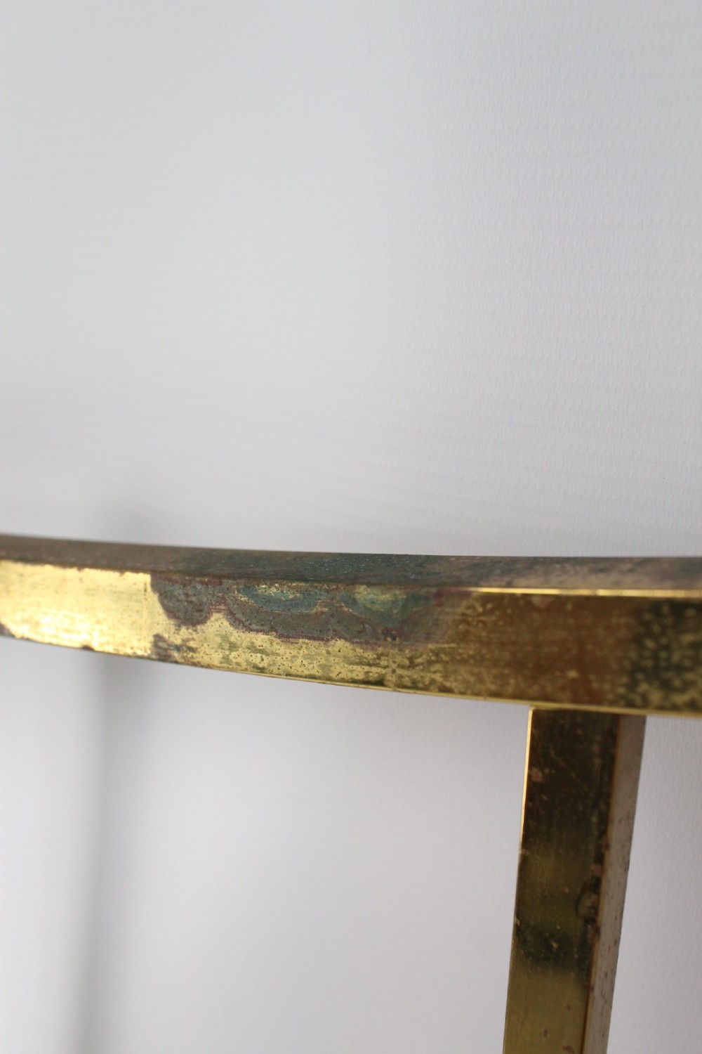 A Victorian brass single bed frame featuring a gently curved top rail, vertical spindles, turned finials, and original wheel castors. View X