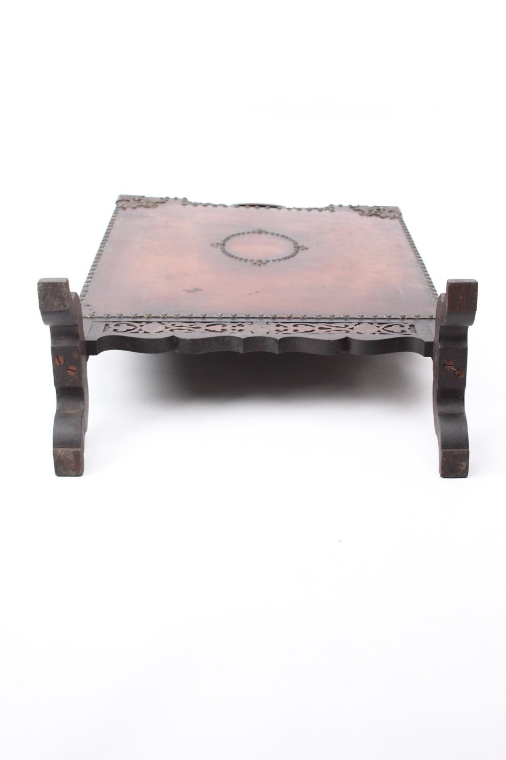 An Edwardian Arts and Crafts fire screen constructed from carved oak and warm brown leather featuring brass studwork and a central oval motif. View V
