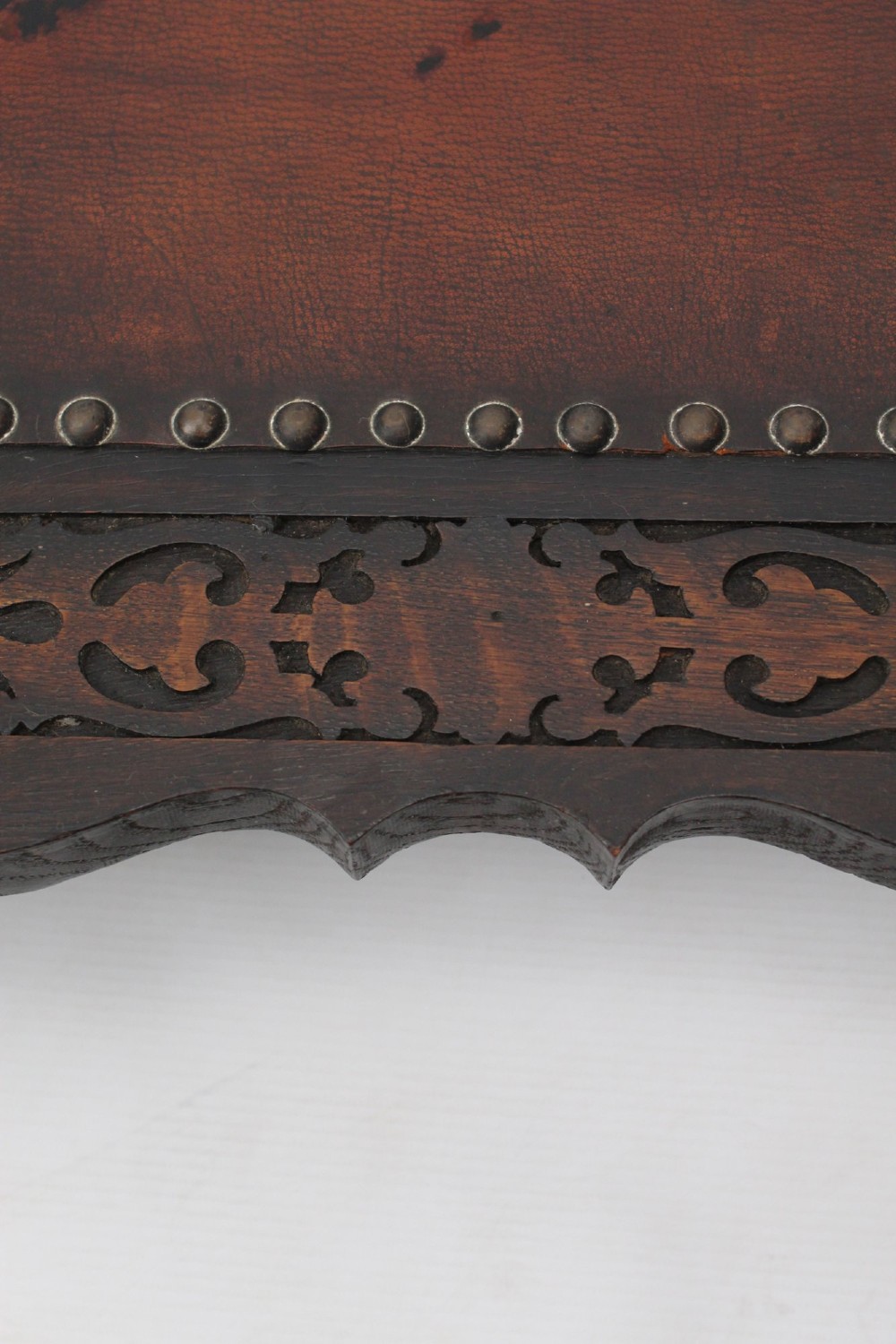 An Edwardian Arts and Crafts fire screen constructed from carved oak and warm brown leather featuring brass studwork and a central oval motif. View VI