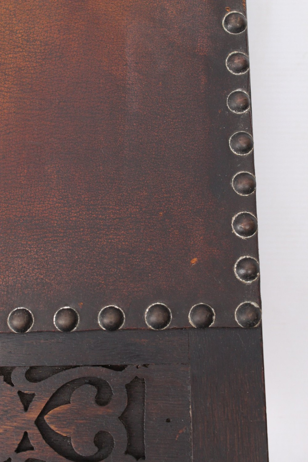An Edwardian Arts and Crafts fire screen constructed from carved oak and warm brown leather featuring brass studwork and a central oval motif. View VIII
