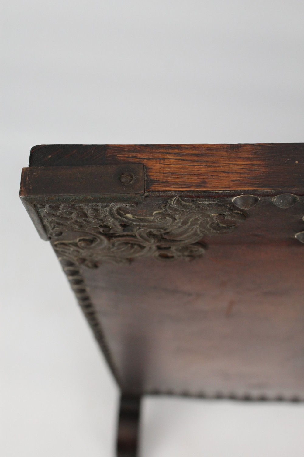 An Edwardian Arts and Crafts fire screen constructed from carved oak and warm brown leather featuring brass studwork and a central oval motif. View IX