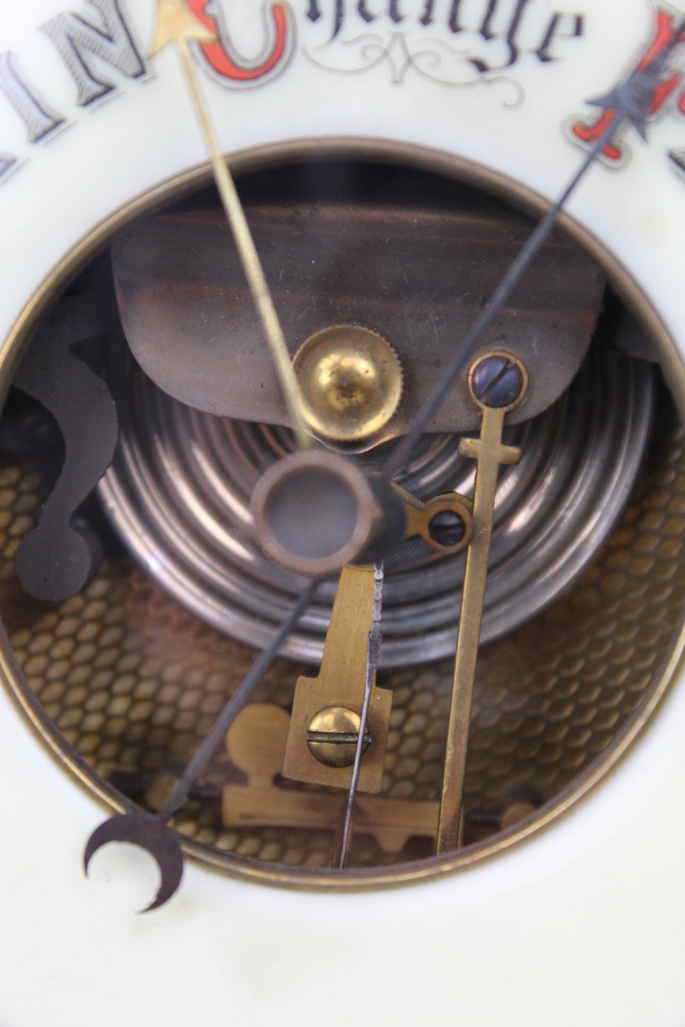 A circular Victorian walnut wall barometer featuring a carved wooden border, a brass hanging ring, and an exposed brass skeleton movement within an enamel dial. View VIII