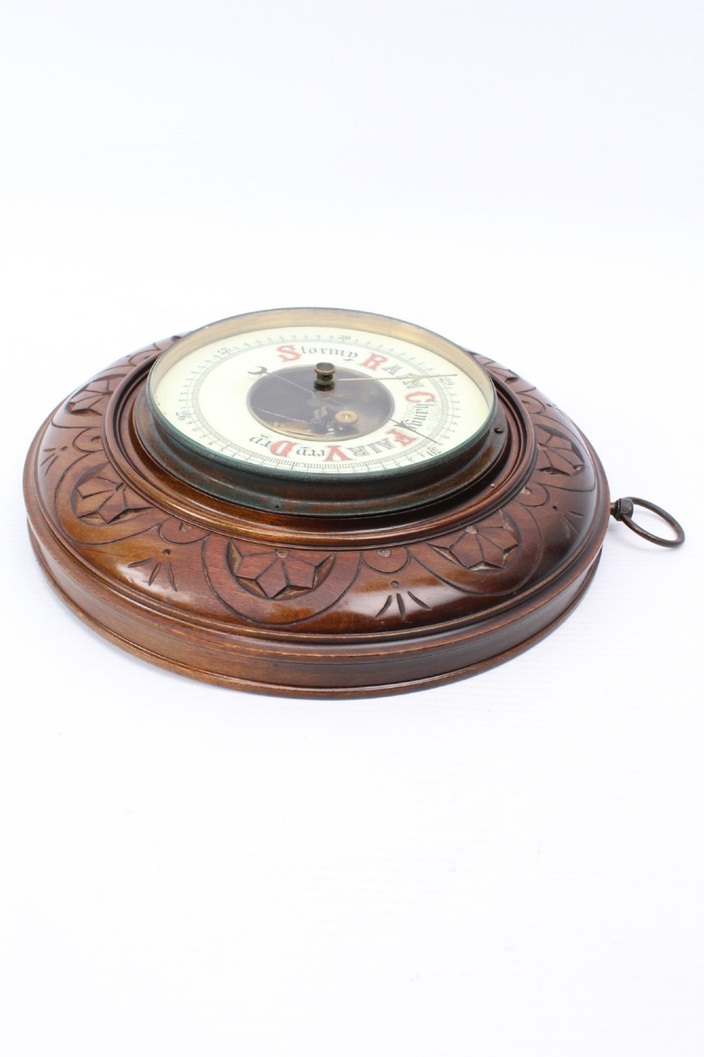 A circular Victorian walnut wall barometer featuring a carved wooden border, a brass hanging ring, and an exposed brass skeleton movement within an enamel dial. View X