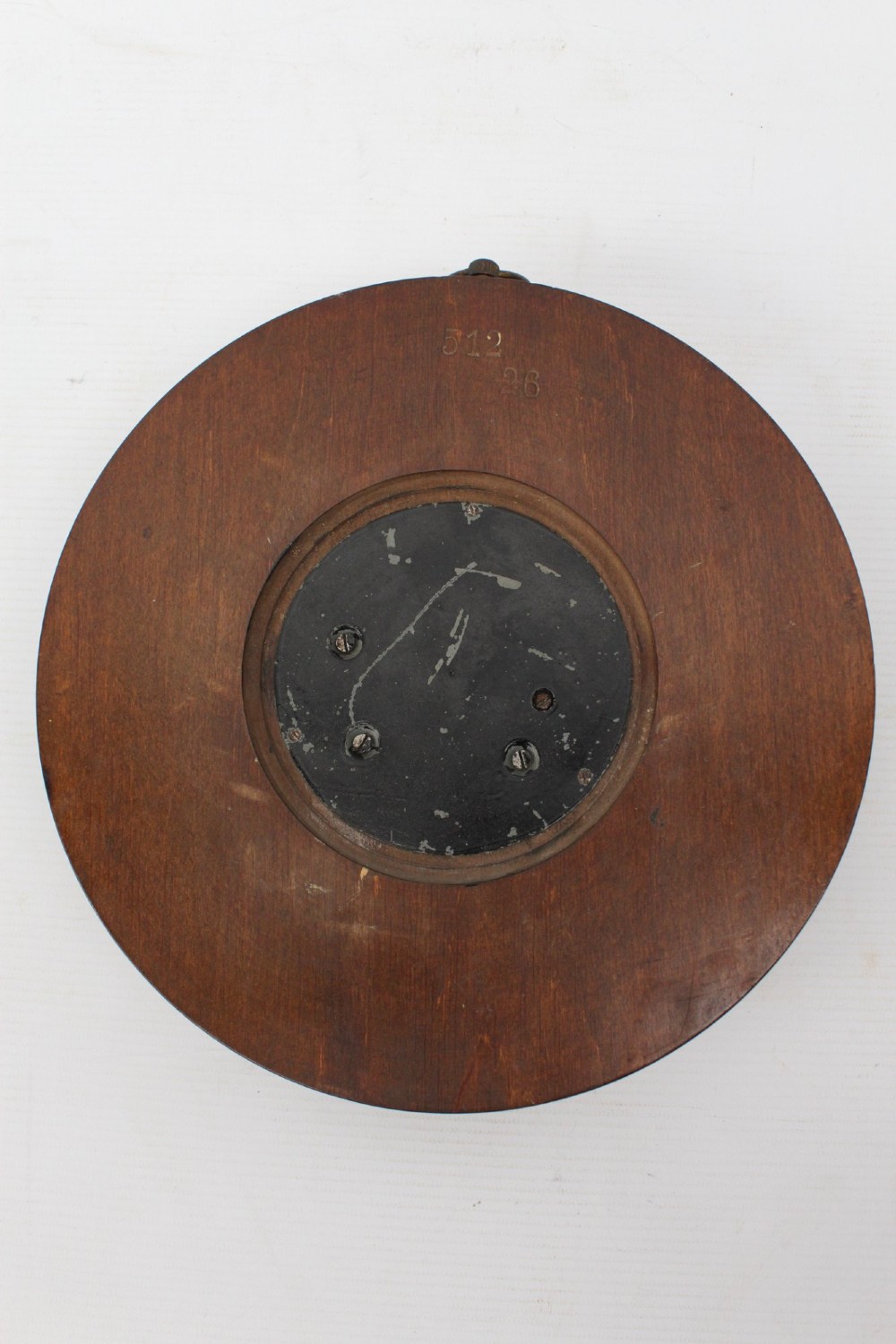 A circular Victorian walnut wall barometer featuring a carved wooden border, a brass hanging ring, and an exposed brass skeleton movement within an enamel dial. View XII