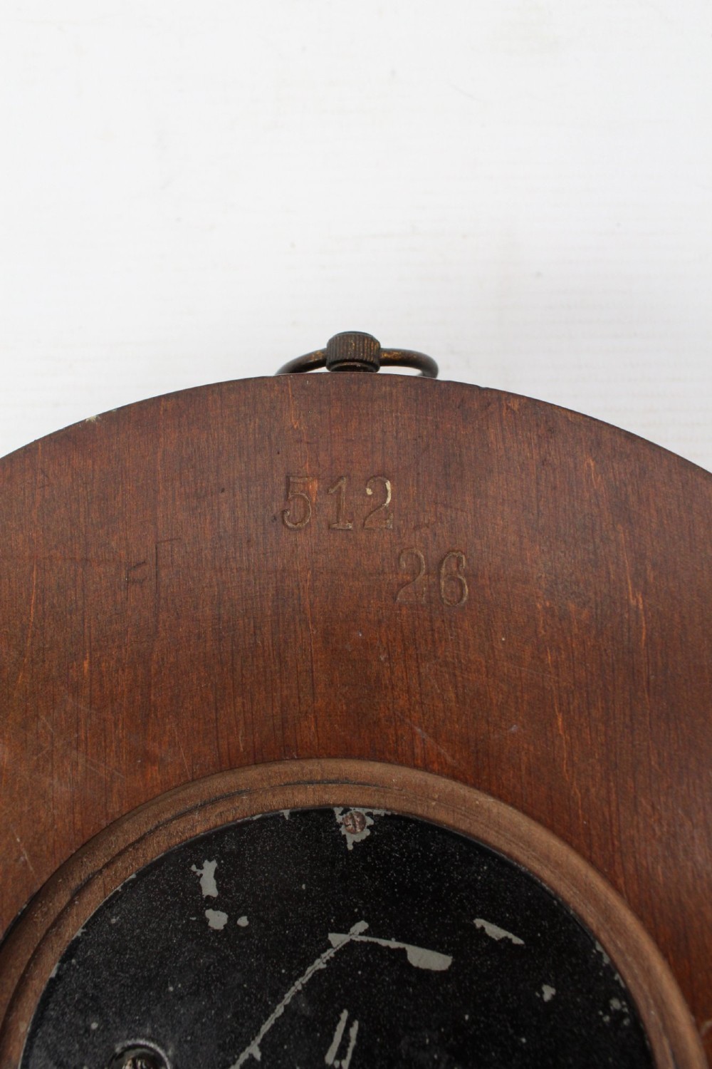 A circular Victorian walnut wall barometer featuring a carved wooden border, a brass hanging ring, and an exposed brass skeleton movement within an enamel dial. View XIII