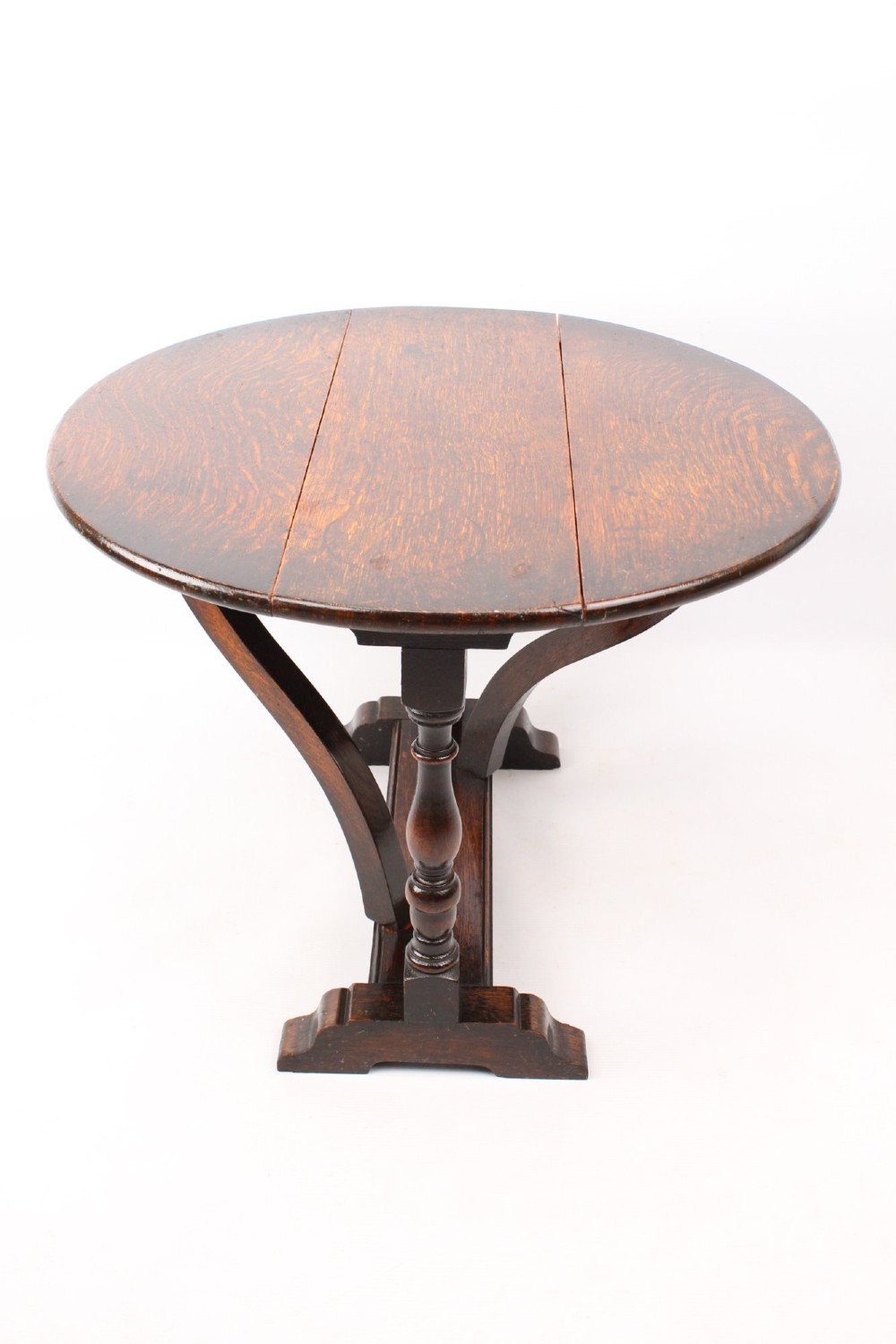 A dark oak drop-leaf coffee table featuring hinged side flaps, turned legs, and a sturdy trestle base. View V