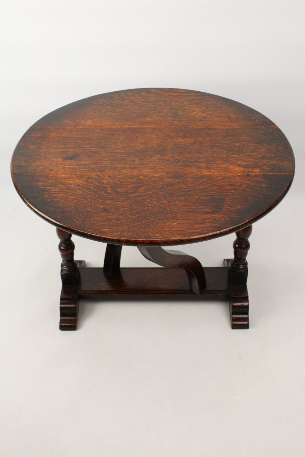 A dark oak drop-leaf coffee table featuring hinged side flaps, turned legs, and a sturdy trestle base. View VI