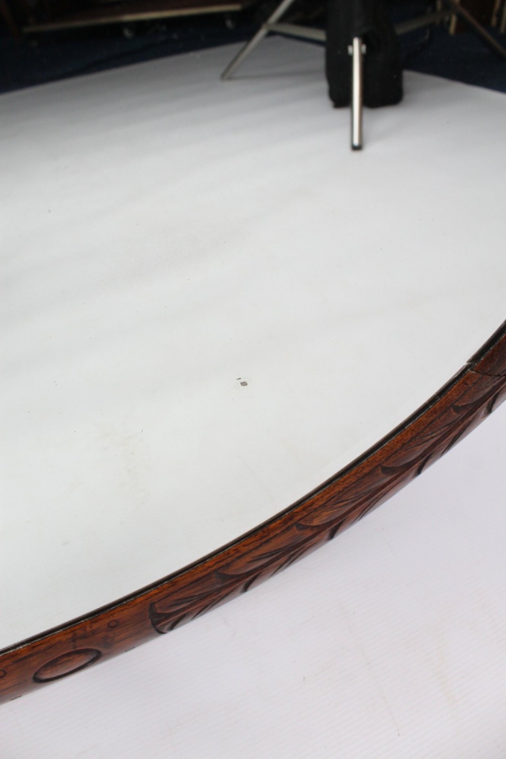 An Edwardian oval wall mirror featuring a carved dark oak frame decorated with leaf motifs and rounded bosses. View XII