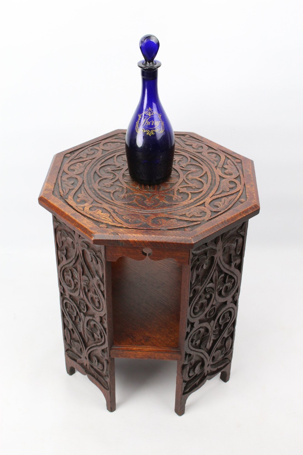 An Edwardian hexagonal dark oak side table featuring intricate relief carving on the top surface and side panels. View II