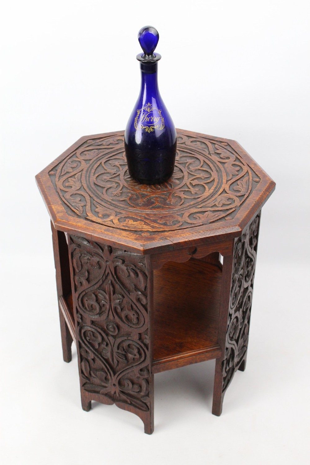An Edwardian hexagonal dark oak side table featuring intricate relief carving on the top surface and side panels. View III