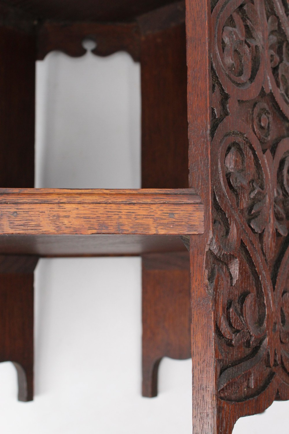An Edwardian hexagonal dark oak side table featuring intricate relief carving on the top surface and side panels. View IX