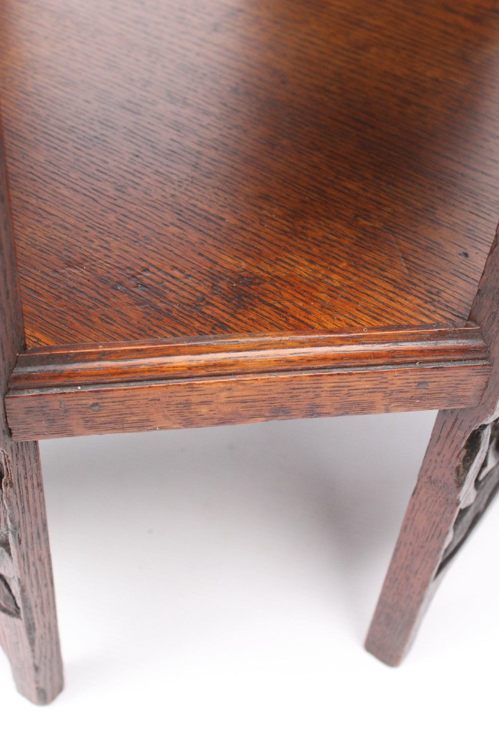 An Edwardian hexagonal dark oak side table featuring intricate relief carving on the top surface and side panels. View X