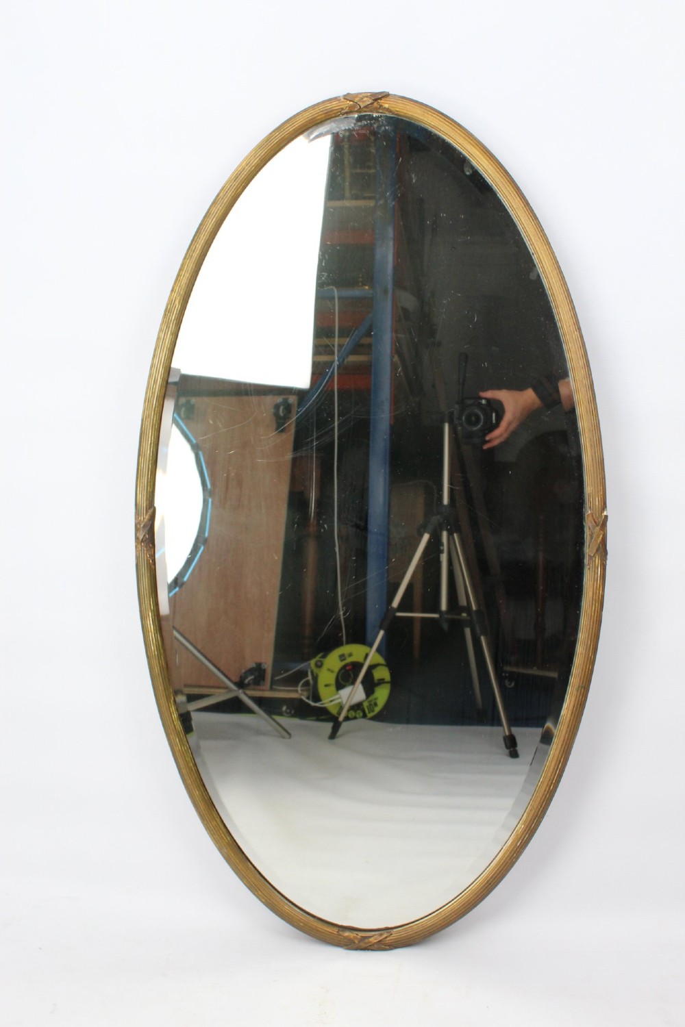 A large Victorian oval wall mirror featuring a gilded reeded frame with decorative cross-ribbon accents at four points. View II