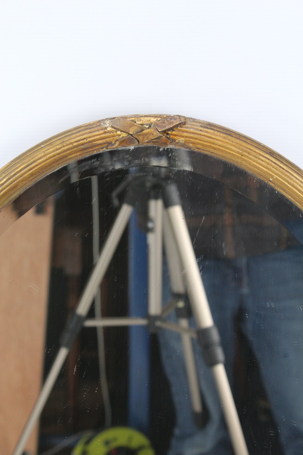 A large Victorian oval wall mirror featuring a gilded reeded frame with decorative cross-ribbon accents at four points. View IV