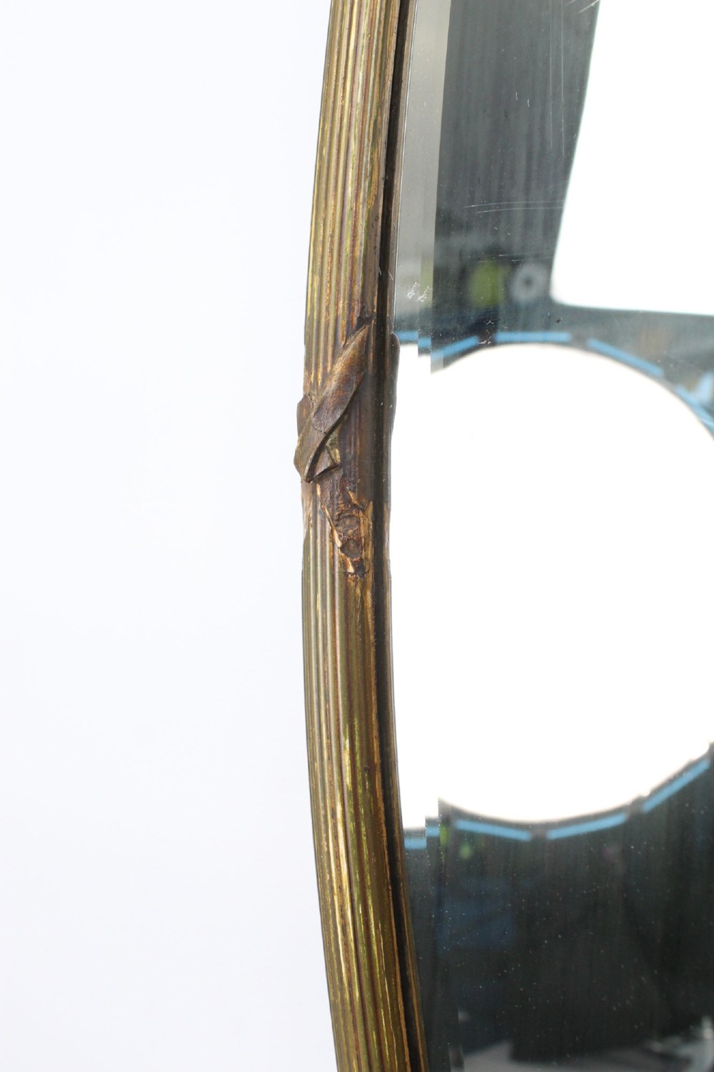 A large Victorian oval wall mirror featuring a gilded reeded frame with decorative cross-ribbon accents at four points. View IX