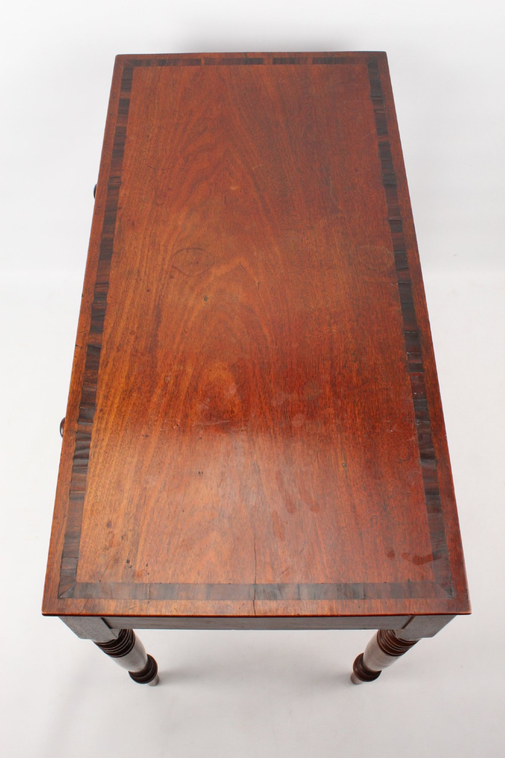 A Regency mahogany writing desk featuring brass inlaid corner stiles, two frieze drawers with wooden knobs, and turned legs. View III