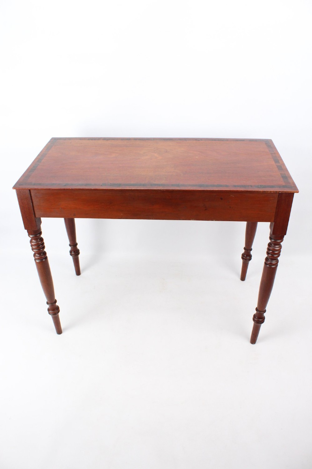 A Regency mahogany writing desk featuring brass inlaid corner stiles, two frieze drawers with wooden knobs, and turned legs. View IV