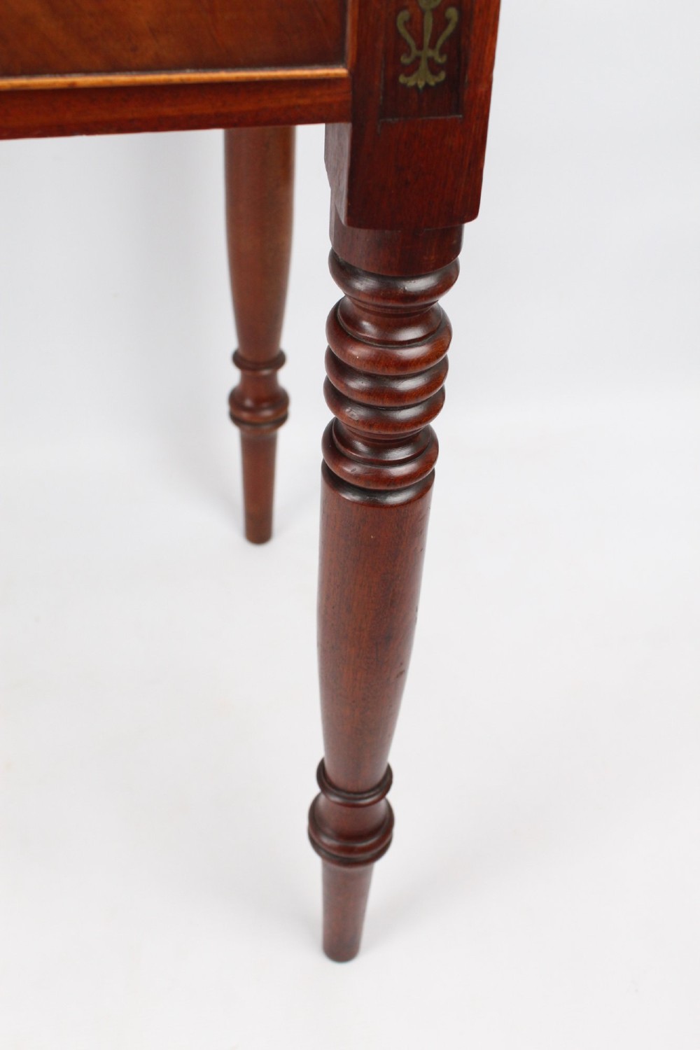 A Regency mahogany writing desk featuring brass inlaid corner stiles, two frieze drawers with wooden knobs, and turned legs. View VIII