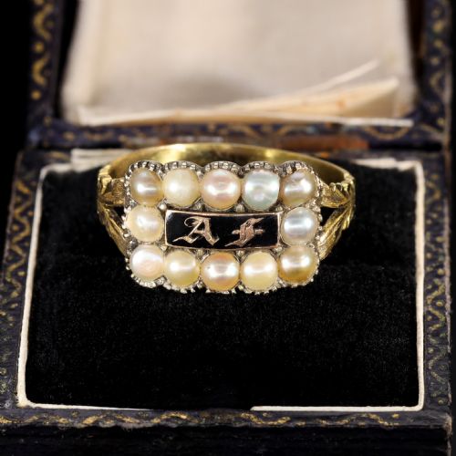 fig 1. A Victorian gold ring featuring a central rectangular black enamel plaque with gold gothic initials surrounded by twelve seed pearls and chased shoulders.