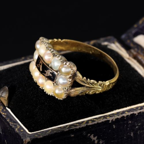 fig 2. A Victorian gold ring featuring a central rectangular black enamel plaque with gold gothic initials surrounded by twelve seed pearls and chased shoulders.