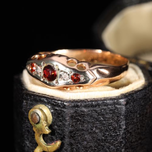fig 2. A vintage 1929 gold ring featuring a carved bridge setting mounted with central deep red garnets and small accent diamonds.