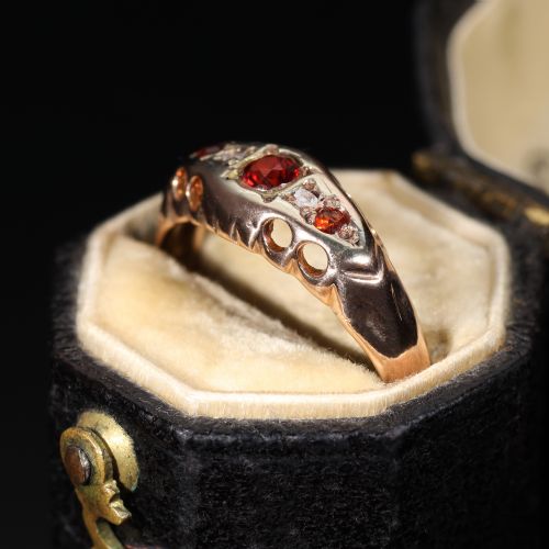fig 3. A vintage 1929 gold ring featuring a carved bridge setting mounted with central deep red garnets and small accent diamonds.