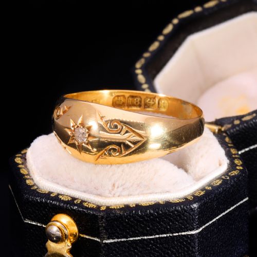 fig 1. An 18ct yellow gold Victorian band ring featuring a starburst-set diamond surrounded by hand-carved scroll engraving and visible internal hallmarks.
