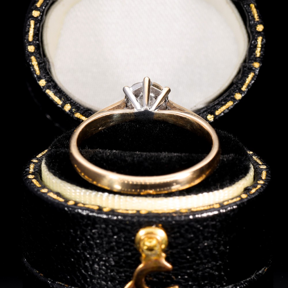 A yellow gold solitaire ring featuring a round clear diamond held within a star-shaped white metal illusion setting. View III