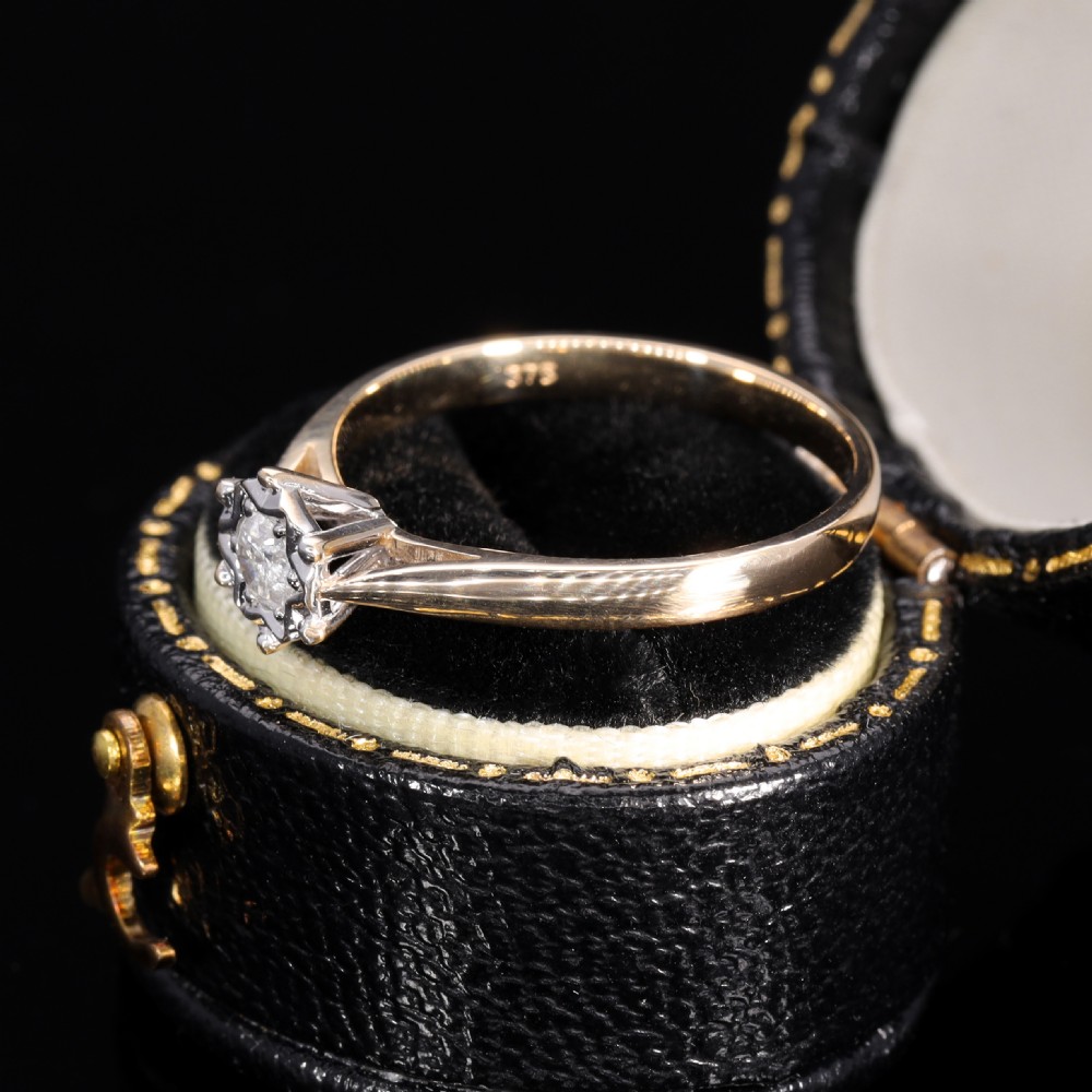 A yellow gold solitaire ring featuring a round clear diamond held within a star-shaped white metal illusion setting. View V