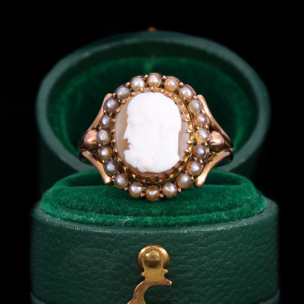 A Victorian yellow gold ring set with an oval carved shell cameo profile encircled by a halo of seed pearls.