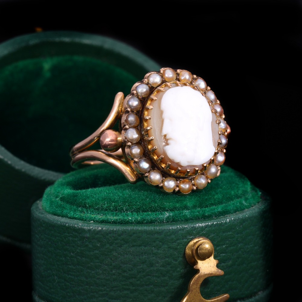 A Victorian yellow gold ring set with an oval carved shell cameo profile encircled by a halo of seed pearls. View II