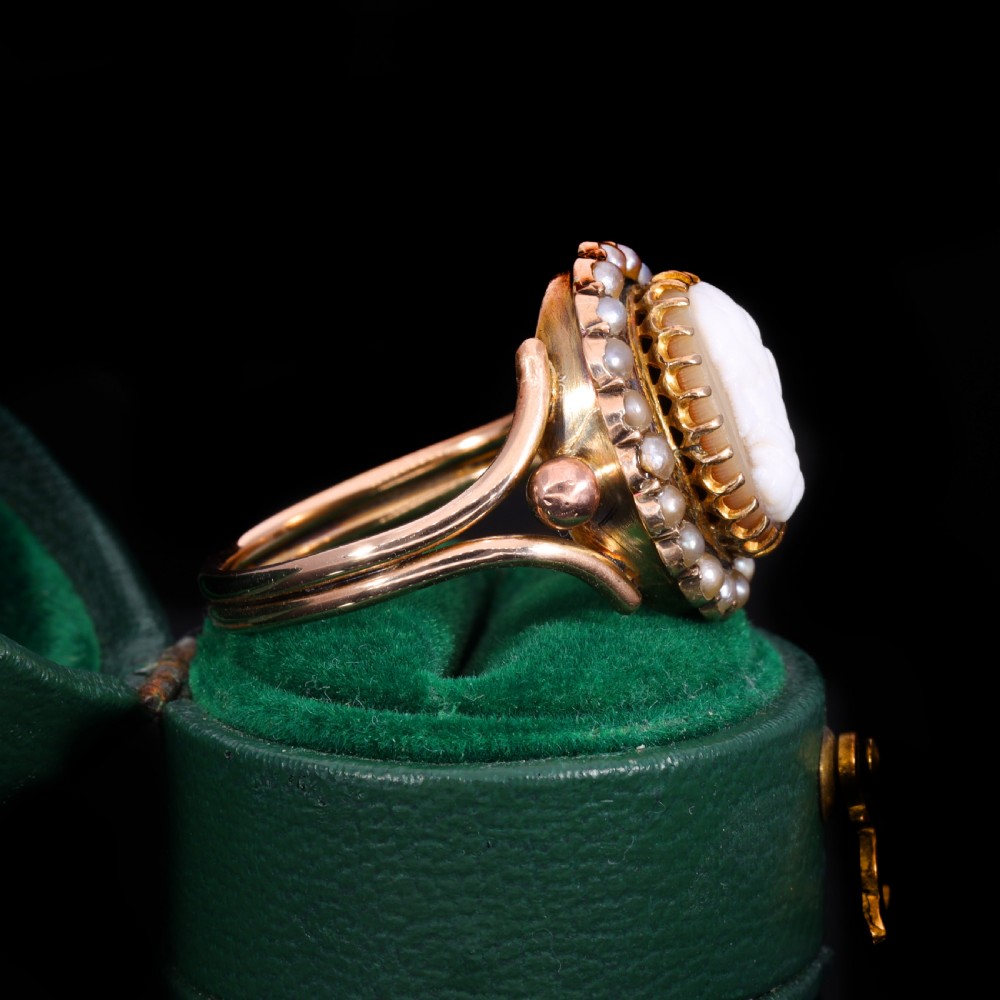 A Victorian yellow gold ring set with an oval carved shell cameo profile encircled by a halo of seed pearls. View IV