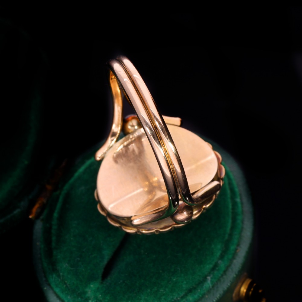 A Victorian yellow gold ring set with an oval carved shell cameo profile encircled by a halo of seed pearls. View VI