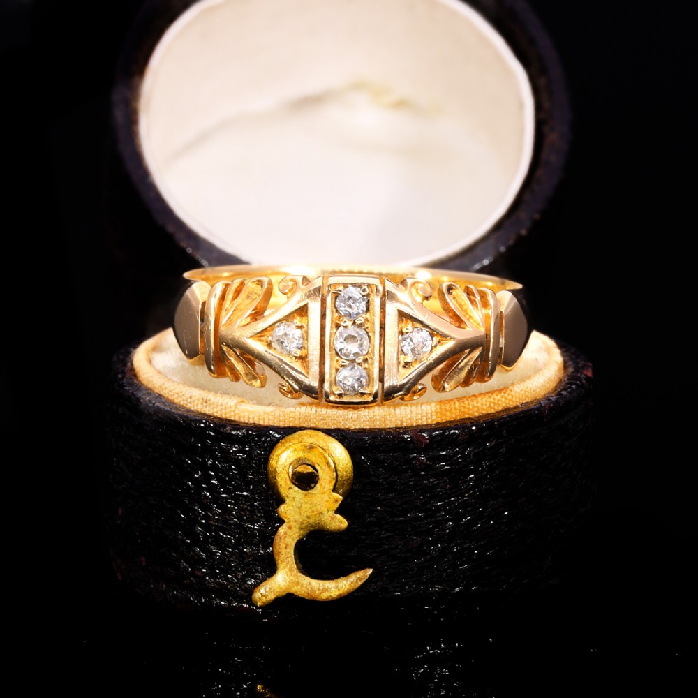 An Edwardian yellow gold ring featuring five inset diamonds within an ornate engraved pattern band.
