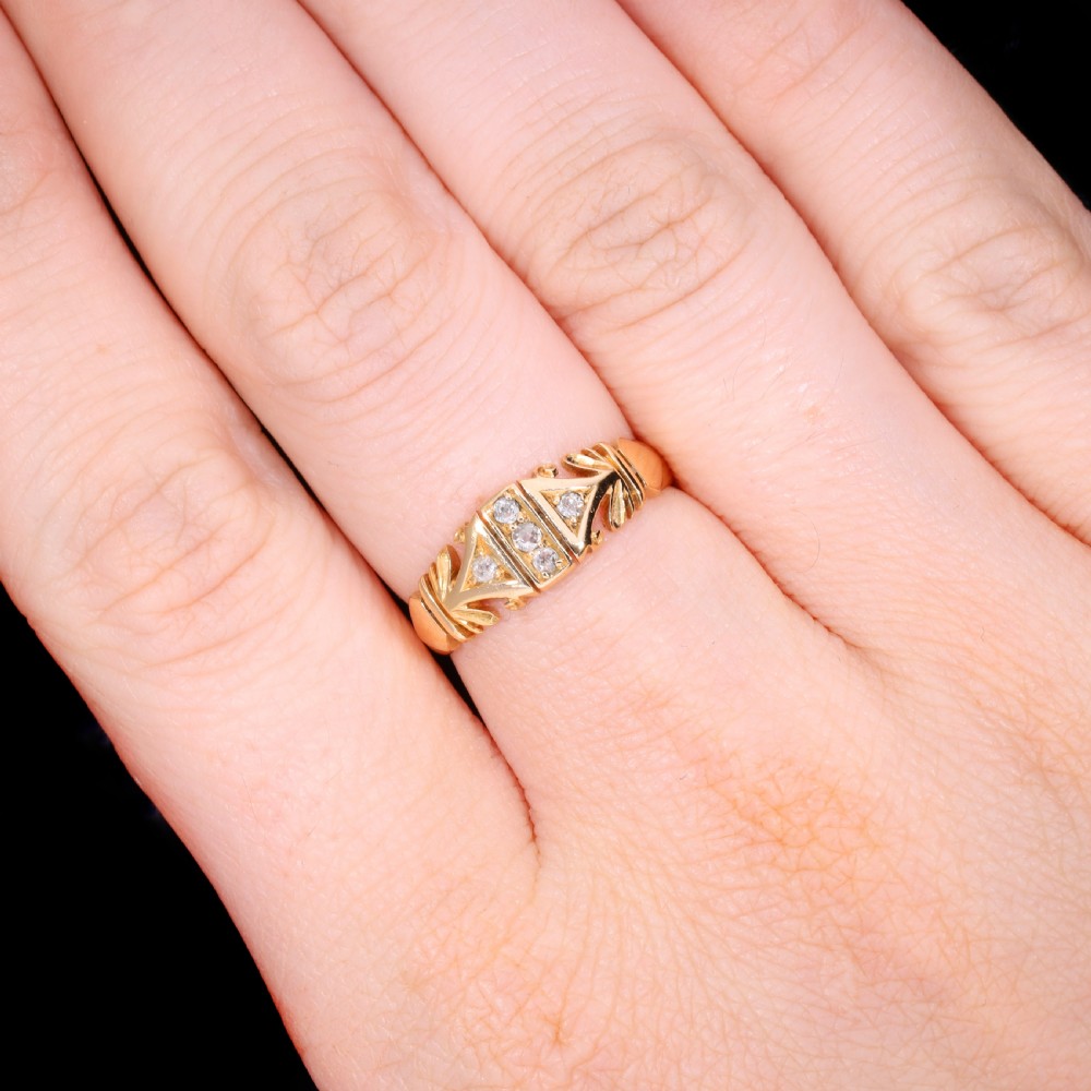 An Edwardian yellow gold ring featuring five inset diamonds within an ornate engraved pattern band. View VI