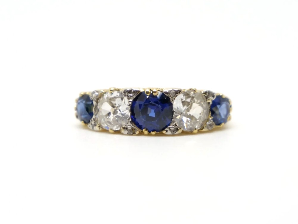 A yellow gold ring set with three blue sapphires alternating with two round diamonds across the front band.