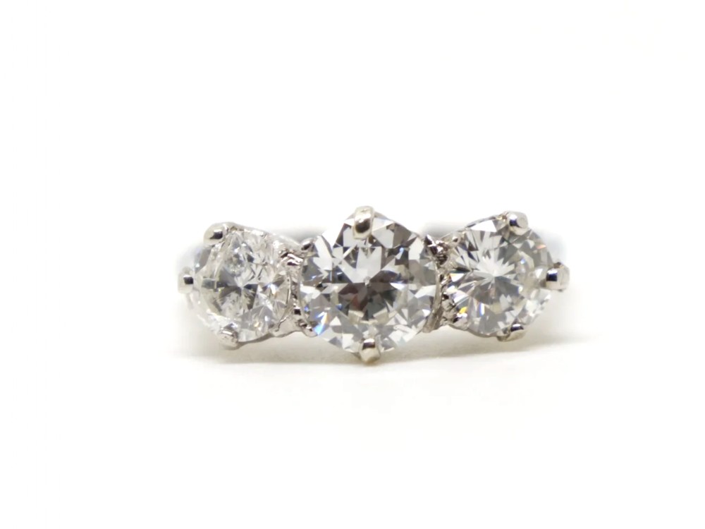 A platinum trilogy ring featuring three claw-set round old cut diamonds in a horizontal alignment.