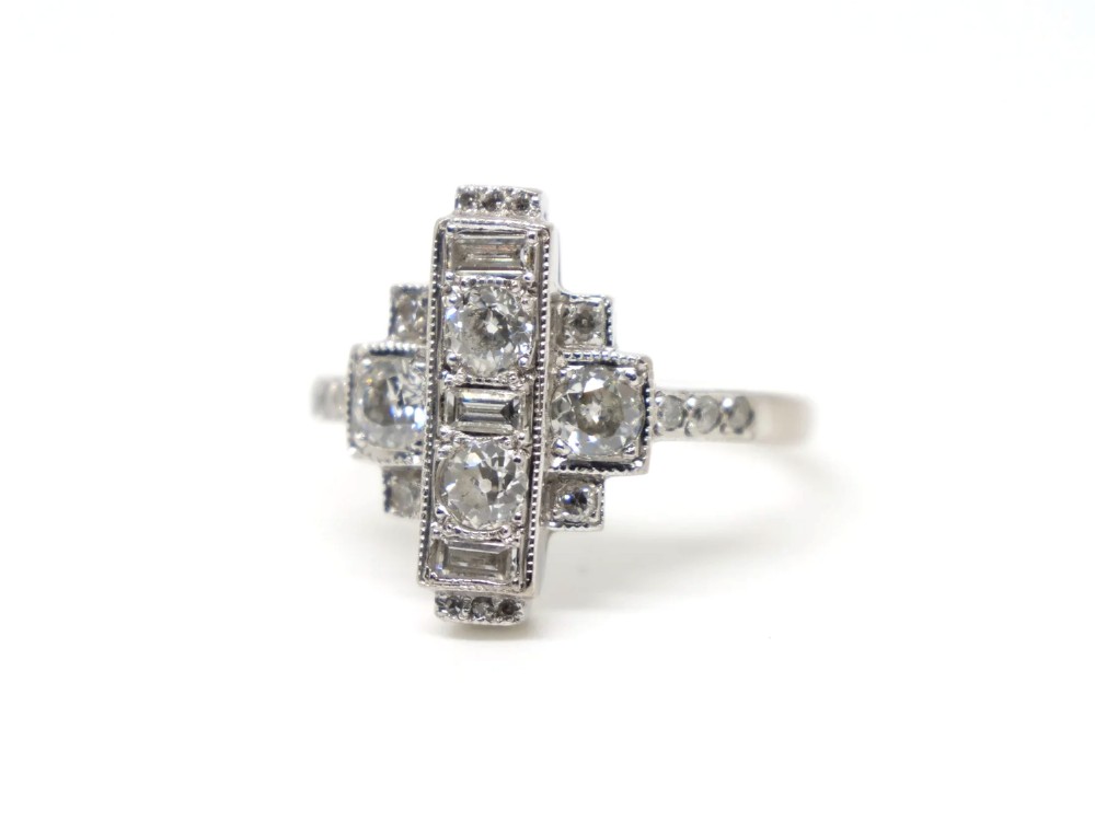An Art Deco 18ct gold ring featuring a geometric stepped plaque design set with round old cut diamonds and baguette cut diamonds. View III