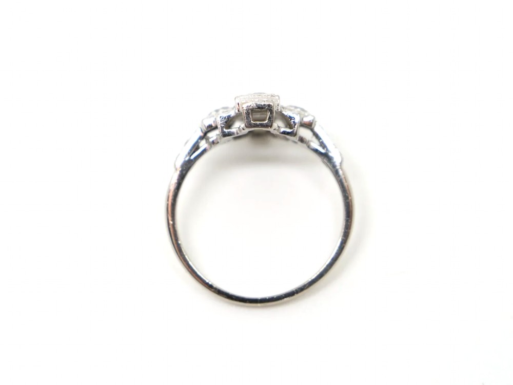 An Art Deco 18ct gold ring featuring a geometric stepped plaque design set with round old cut diamonds and baguette cut diamonds. View IV