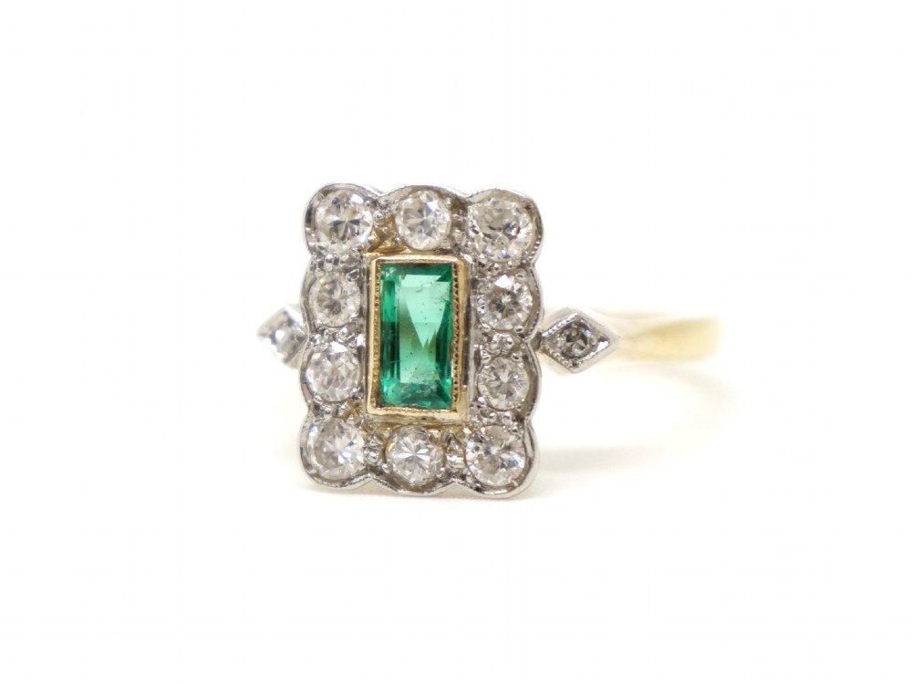 An Art Deco style ring featuring a central emerald-cut green emerald surrounded by a scalloped border of round diamonds set in white metal on a yellow gold band. View III