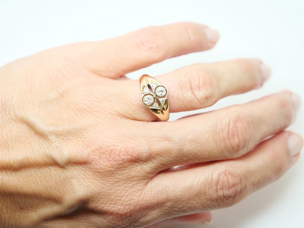 An Art Deco two-stone diamond ring crafted in 18ct yellow gold with a geometric white metal setting featuring two main diamonds and small accent stones. View V