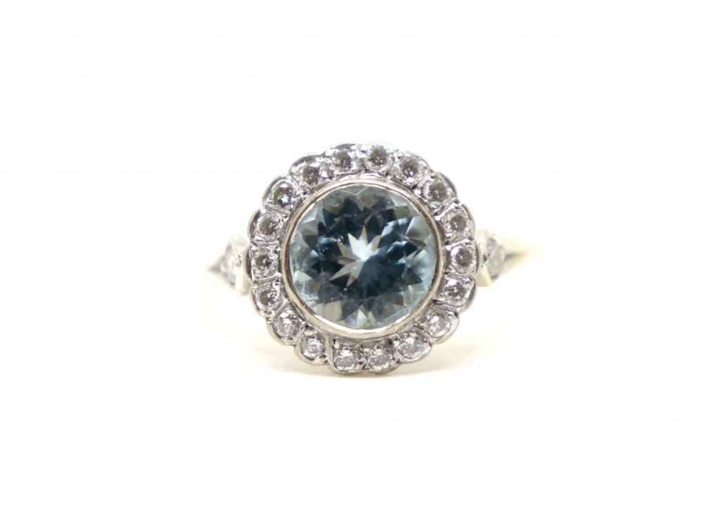 A round-cut light blue aquamarine ring surrounded by a circular diamond halo setting on a gold band.