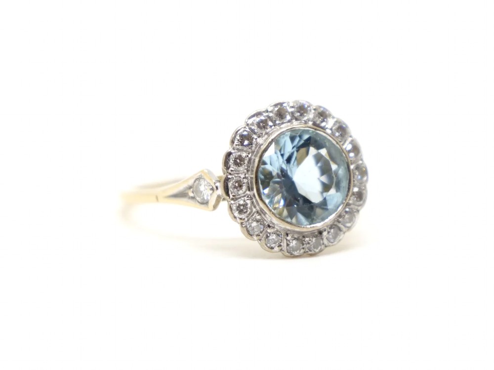 A round-cut light blue aquamarine ring surrounded by a circular diamond halo setting on a gold band. View IV