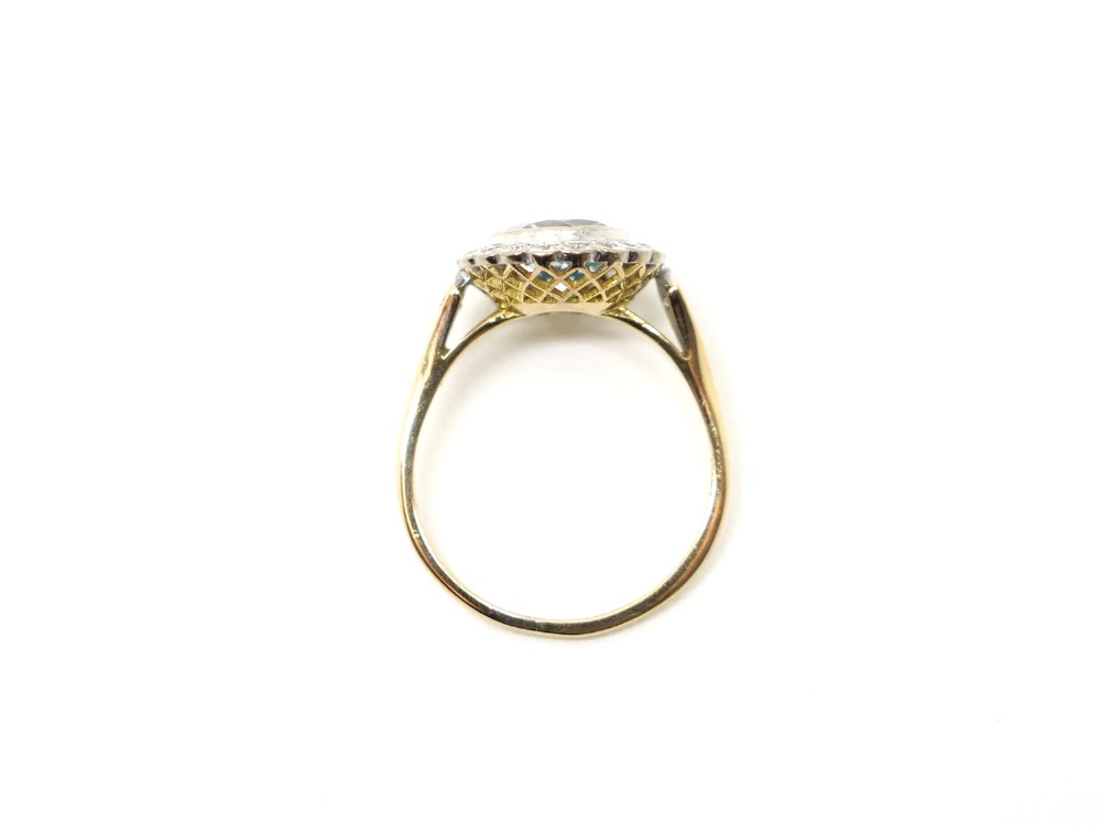 A round-cut light blue aquamarine ring surrounded by a circular diamond halo setting on a gold band. View V