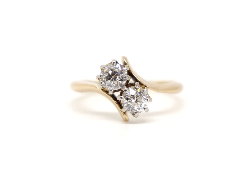 An 18ct yellow gold ring featuring a crossover band set with two round brilliant diamonds in multi-claw settings.