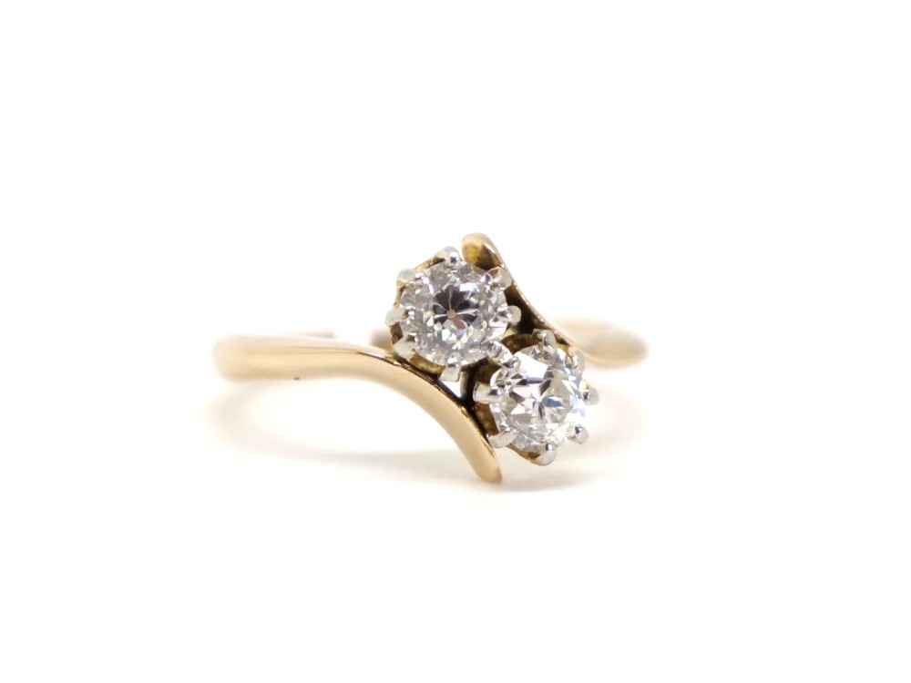 An 18ct yellow gold ring featuring a crossover band set with two round brilliant diamonds in multi-claw settings. View II