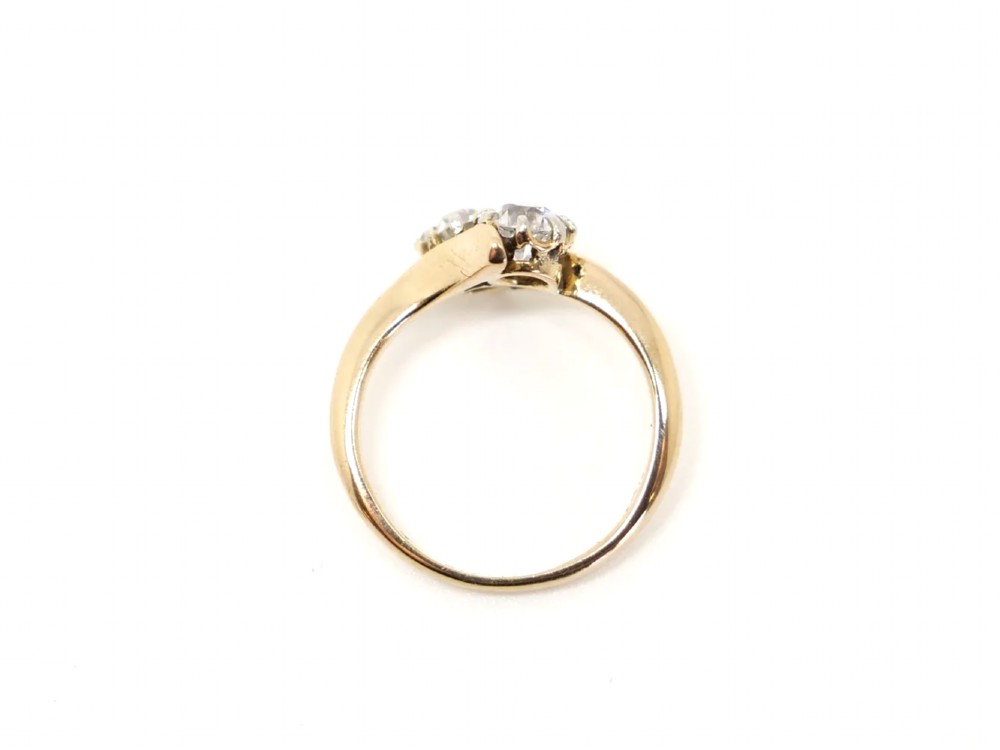 An 18ct yellow gold ring featuring a crossover band set with two round brilliant diamonds in multi-claw settings. View IV