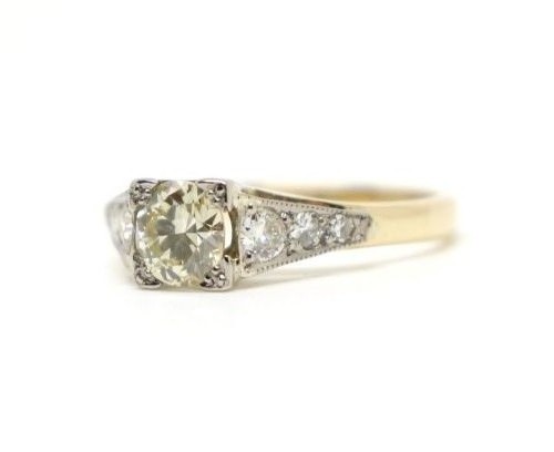 An Art Deco diamond solitaire ring featuring a round central diamond flanked by diamond-set shoulders on a two-tone band. View II