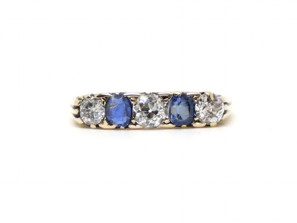 An 18ct yellow gold five-stone ring set with alternating round diamonds and oval blue sapphires in claw mounts.